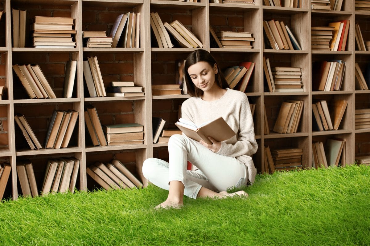 Portrait of beautiful young woman with book in library