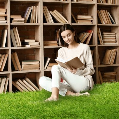 Portrait of beautiful young woman with book in library