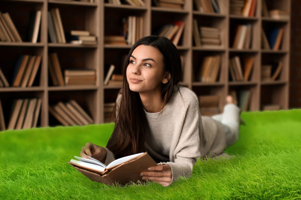 Portrait of beautiful young woman with book in library