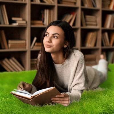 Portrait of beautiful young woman with book in library