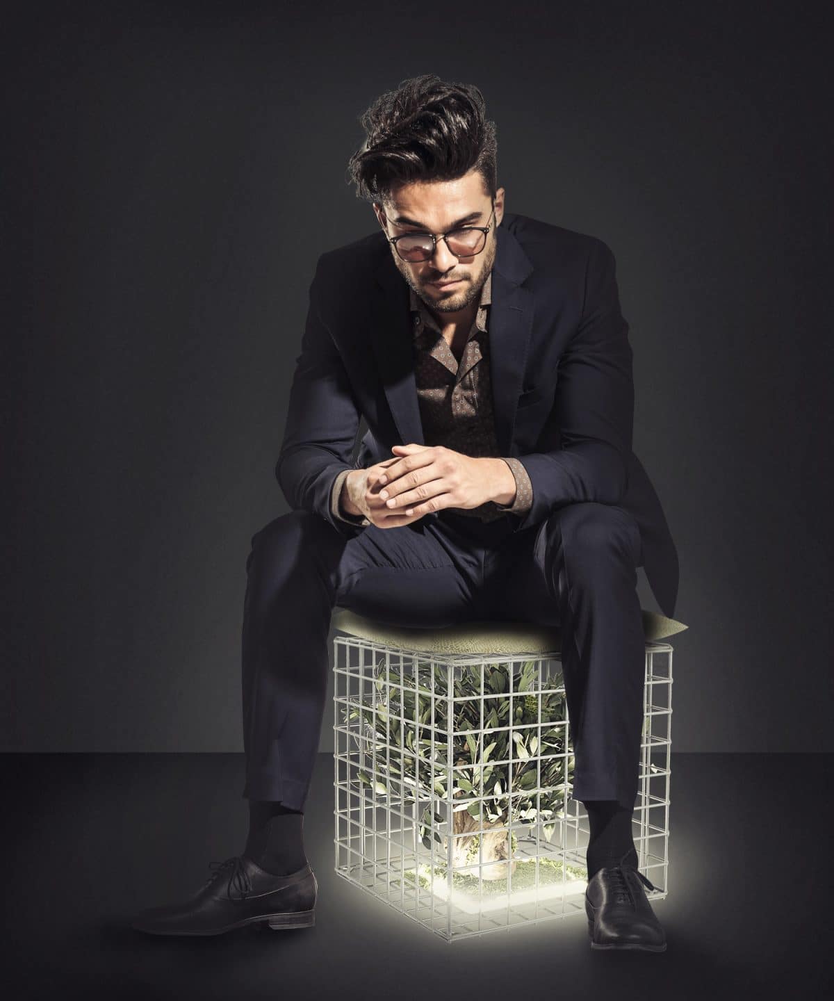 young business man sitting on chair and looking down, on grey studio background