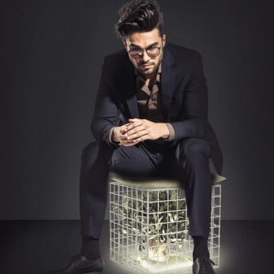 young business man sitting on chair and looking down, on grey studio background
