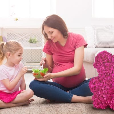Little girl and her mom eating salad at home